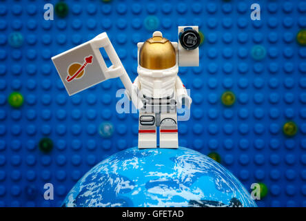 Tambov, Russian Federation - July 06, 2016 Lego spaceman minifigure with flag stay on planet against Lego blue baseplate. Stock Photo