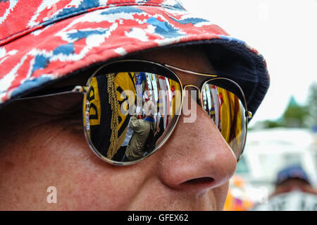 Belfast, Northern Ireland. 10th August 2013 - Union flags and loyalist supporters are reflected in the sunglasses of a man gathered at a flag protest. Stock Photo