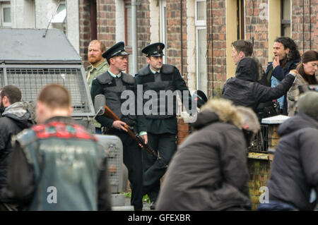 Belfast, Northern Ireland. 18 Dec 2014 - Actors dressed as Royal Ulster Constabulary (RUC) officers and Irish Republicans stand on a street in Belfast during a music video shoot for U2s 'Every Breaking Wave'. Stock Photo