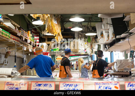 Seattle, Washington: Tourist catches a fish as mongers look on at Pike Place Fish Market. Stock Photo