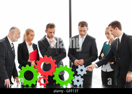 Business people assembling cogwheels, teamwork concept Stock Photo