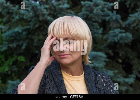 Elderly woman is having a headache and touching her head with her right hand Stock Photo