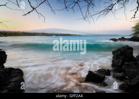 Beach and waves with Hualalai volcano in background. Hawaii Island Stock Photo