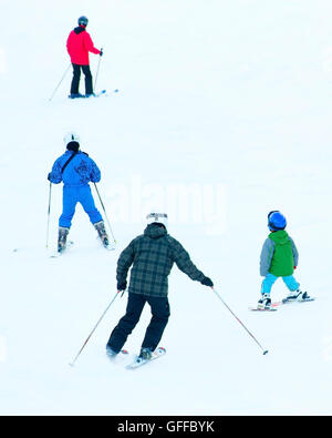 Group of a skiers on a mountain slope at ski resort. Back view Stock Photo