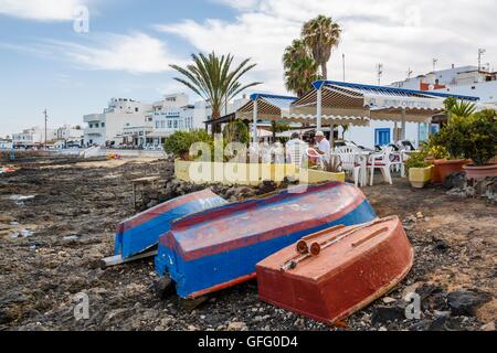 A line of rowing boats moored at an old wooden jetty at ...