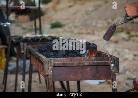 Heating coals on a barbecue in the field campsite Stock Photo