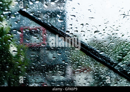 raindrops and wiper on car windshield. use wipers and drive slowly in the rain for safety. Stock Photo