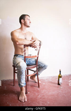 Man with a bottle of wine sitting on a chair Stock Photo