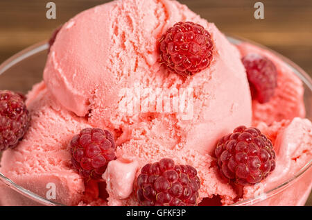 close up of delicious dessert raspberry pink ice cream scoops with fresh raspberries on wooden background Stock Photo