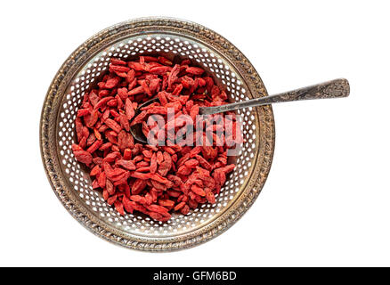 Antique metal bowl of raw dried goji berries with vintage teaspoon inside isolated on white Stock Photo