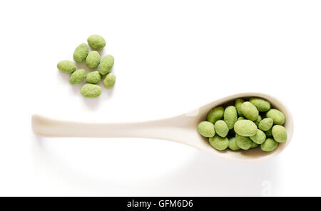 White porcelain spoon with wasabi coated peanuts isolated on white Stock Photo