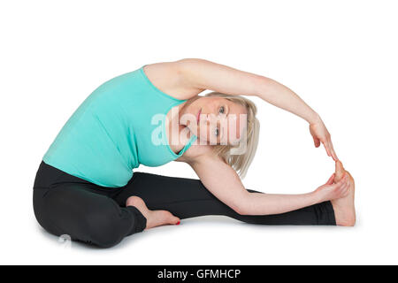 Full body view of a young blond woman in yoga exercise 'sit i of half leg straddle and the upper body to the left leg stretched' Stock Photo