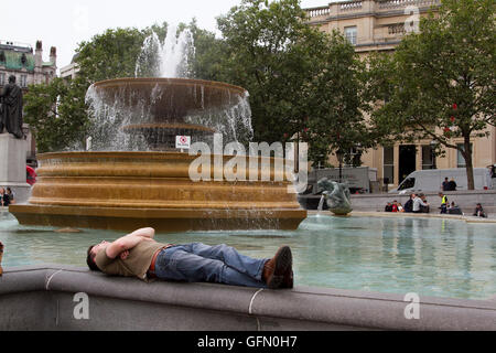 London,UK. 1st August 2016. A man snoozes on the edge of Trafalgar Square fountain on a warm overcast day in London Credit:  amer ghazzal/Alamy Live News Stock Photo