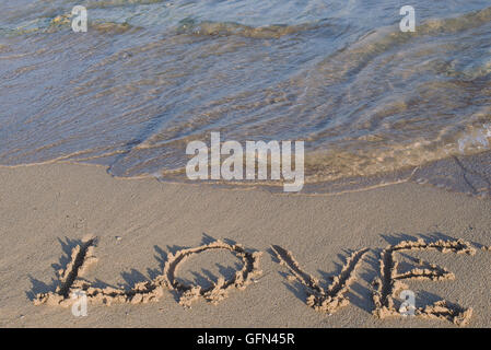 Love - drawn on sea beach sand Stock Photo