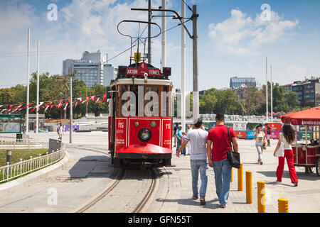 Istanbul, Turkey - July 1, 2016: Vintage red tram goes on Taksim square in Istanbul, ordinary people walk nearby Stock Photo