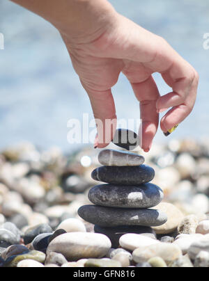 balancing pebble tower with female hand Stock Photo