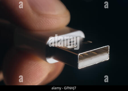 Hand holding white USB cable. Man's hand holds a USB Connector. Closeup man hand holding USB cable. Stock Photo