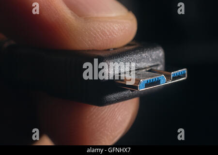 Hand holding black micro USB 3.0 cable. Man's hand holds a USB Connector. Closeup man hand holding USB cable. Stock Photo