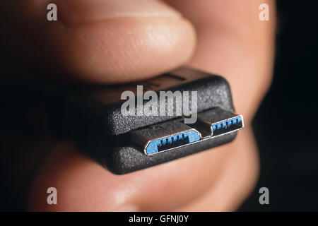 Hand holding black micro USB 3.0 cable. Man's hand holds a USB Connector. Closeup man hand holding USB cable Stock Photo
