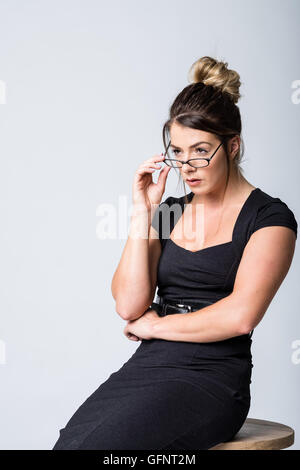 Woman in her 20s looking over her glasses at subject out of frame Stock Photo