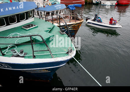 Inuit family coming into the harbor in a small boat, Ilulissat Greenland Stock Photo