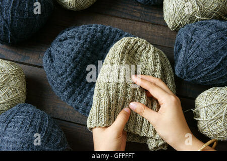 Handmade gift for couple on wintertime, woollen hat in black and beige color, woman hand knitting from ball of yarn Stock Photo