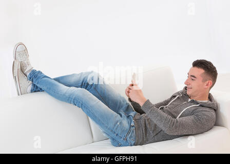 Young man lying on a couch and chating with martphine Stock Photo