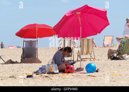 Woman in the shade of a Parasol on Great Yarmouth beach Stock Photo
