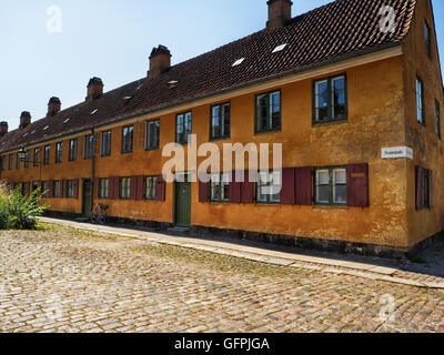Row of terraced orange houses with cobbled street in Nyboder Stock Photo