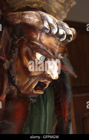 Image in wood of the devil supporting a font in the church at Rennes-le-Chateau, France Stock Photo