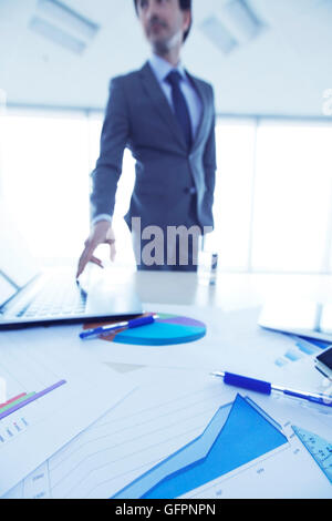 Businessman in office pressing key on laptop Stock Photo