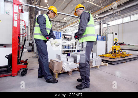 Workers taking aluminium billet at CNC machine shop Stock Photo