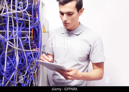Young engeneer man in network server room with digital tablet Stock Photo