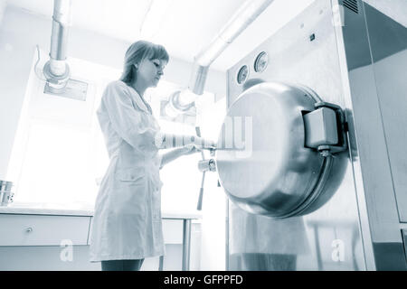 pharmaceutical factory woman worker operating autoclave for medicine drug steam sterilization at pharmacy industry manufacture Stock Photo