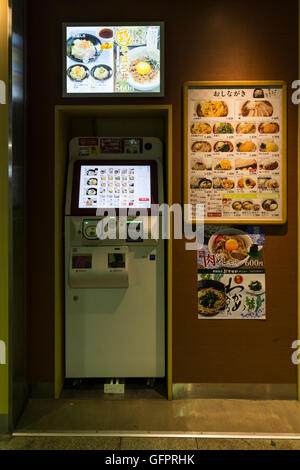A practical vending machine in front of a Japanese noodle bar.