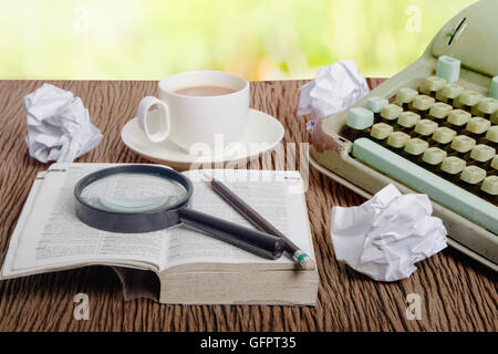 The thai dictionary consider under a magnifier on writer's desk with crumpled sheets around Stock Photo