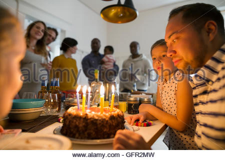 Father and daughters with birthday cake candles at party