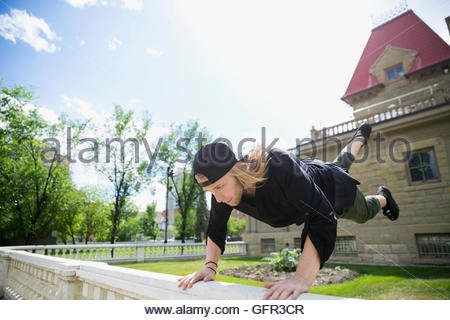Young man doing parkour on railing in sunny garden