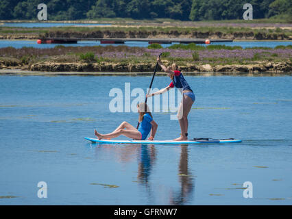 Two girls enjoying stand up paddle boarding in Newtown River on the Isle of Wight, UK Stock Photo