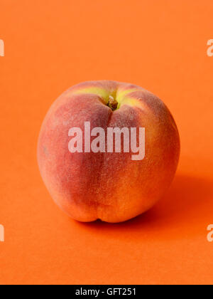 One ripe peach on orange colored background Stock Photo