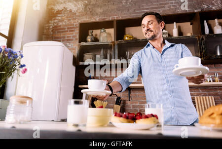 Man putting cups on the table Stock Photo