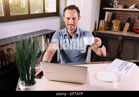 Man using laptop in kitchen Stock Photo