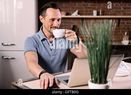 Man looking at laptop in kitchen Stock Photo