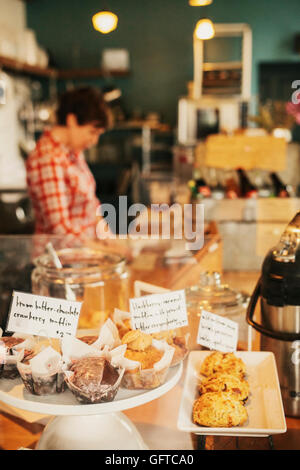Freshly prepared food on the counter of a small coffee shop and restaurant A staff member in the background Stock Photo