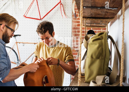 Two men in a cycle repair shop a client looking at backpacks and bike packs Stock Photo