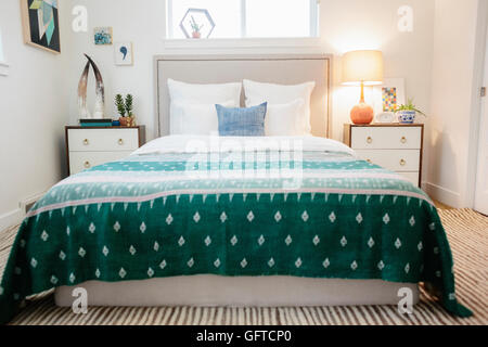 A bedroom in an apartment with a double bed  and a jade green patterned bed cover Stock Photo