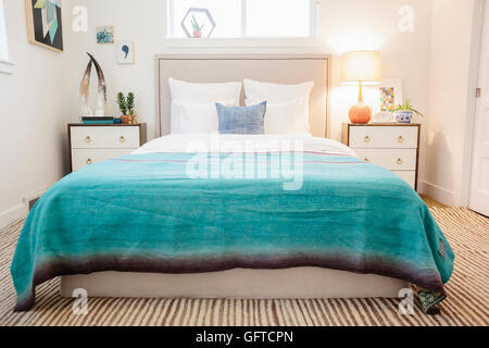 A bedroom in an apartment with a double bed and beside cabinets and a green quilt on the bed Stock Photo