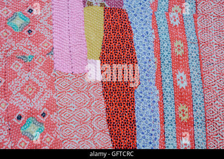 Close up of a fabric bedspread or throw with different fabrics sewn and quilted a retro style and faded look Strips of patterned and plain material Stock Photo