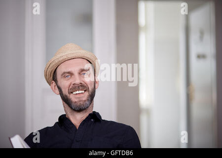 Portrait of hipster with beard and hat laughing to camera Stock Photo
