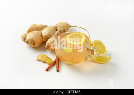 cup of ginger tea with lemon, fresh ginger and cinnamon on white background Stock Photo